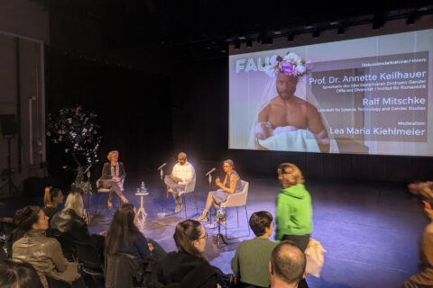 Filmscreening und Diskussion zum Film Feminism WTF an der Friedrich-Alexander-Universität Erlangen-Nürnberg mit drei Menschen auf dem Podium vor Leinwand und Publikum