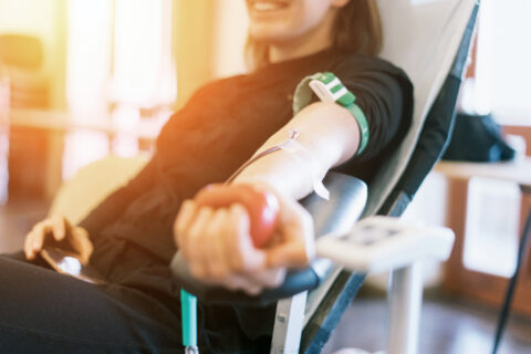 Eine lächelnde Frau leigt auf einer Leige und spendet Blut