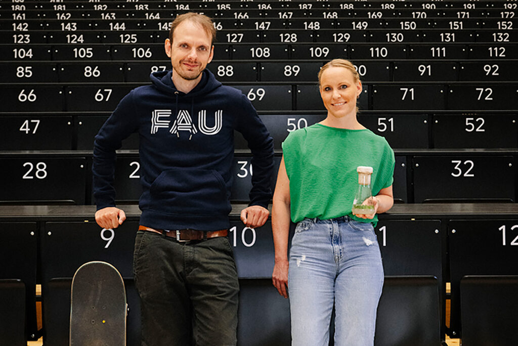 Marcel Bartz mit seinem Skateboard und Jennifer Munkert mit einem Kolben in dem eine Pflanze sich befindet.