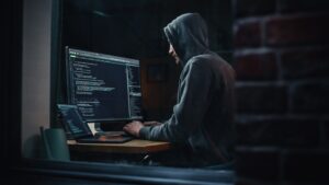 Hacker mit Hoodie am Computer sitzend