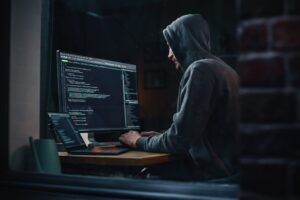 Hacker mit Hoodie am Computer sitzend