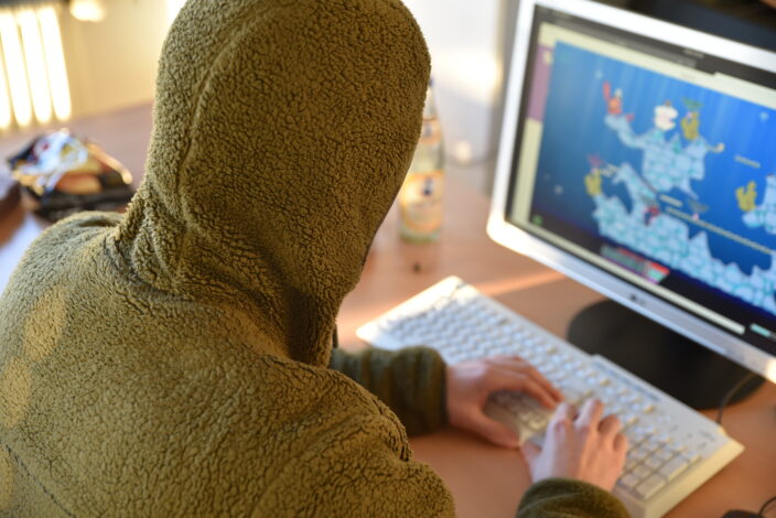 Student als Hacker mit über dem Kopf gezogenem Hoodie