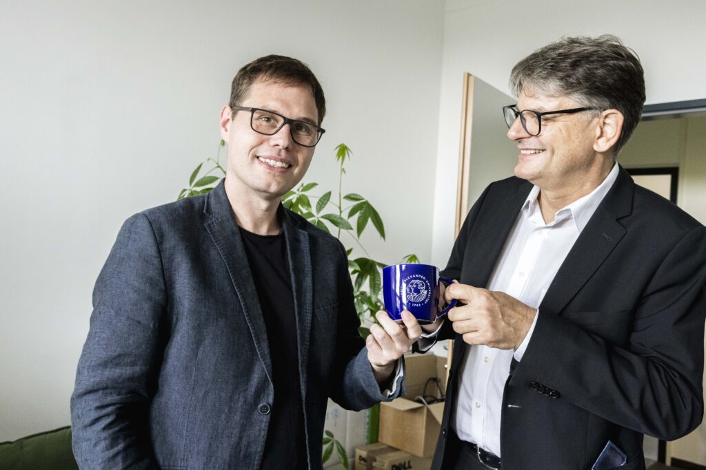 Andreas Kist und FAU-Präsident Hornegger mit einer neuen FAU Tasse.