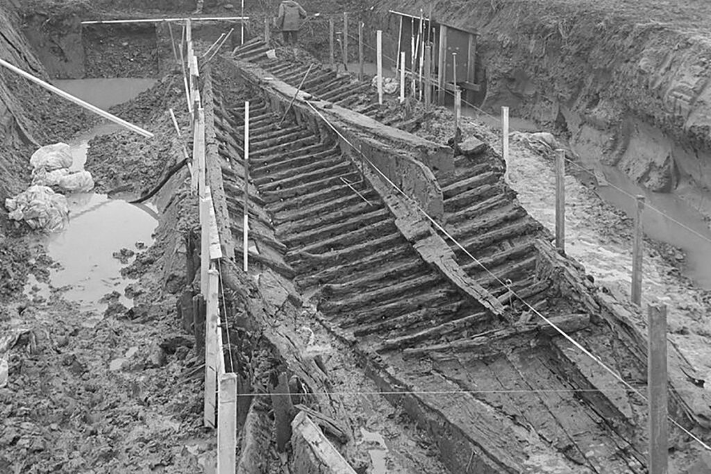 Überreste des Bootes im Schlamm. Nahezu vollständig ausgegraben, sind alle Konstruktionsmerkmale des Boote gut zu erkennen.