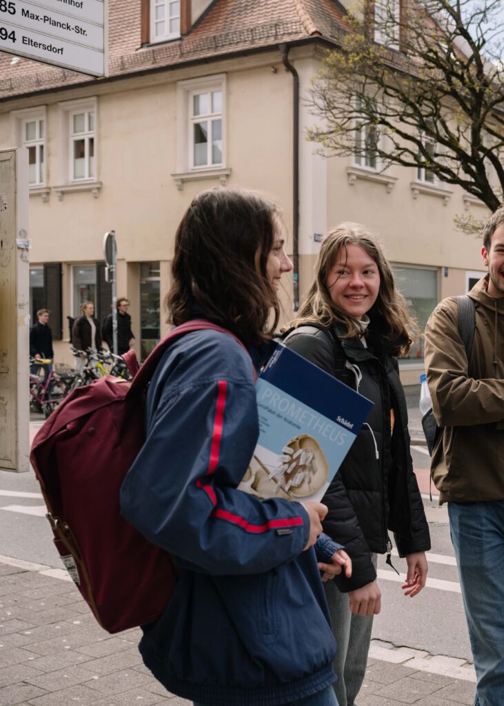 2 Studentinnen draußen mit Buch in der Hand. 